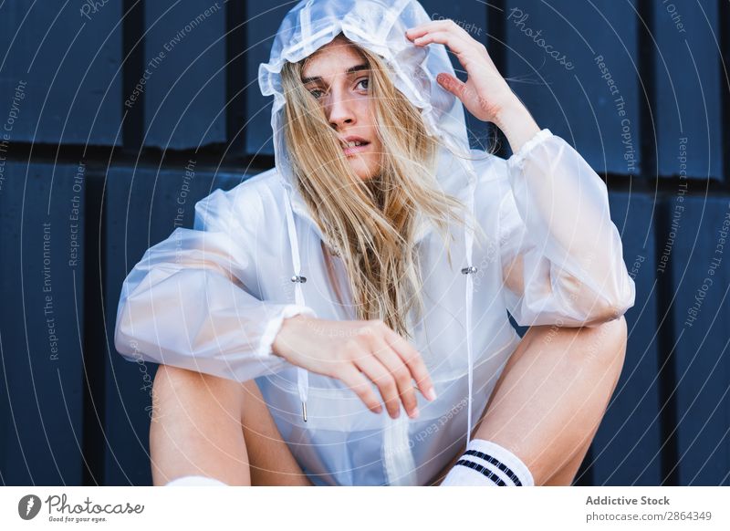 Charming stylish woman in raincoat sitting near wall Woman Blonde Wall (building) Raincoat Street Lady To enjoy jean shorts knee sock Style Sit