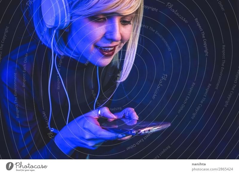 Young woman listening to music Lifestyle Beautiful Face Night life Music Disc jockey Telephone Cellphone Headset Technology Entertainment electronics