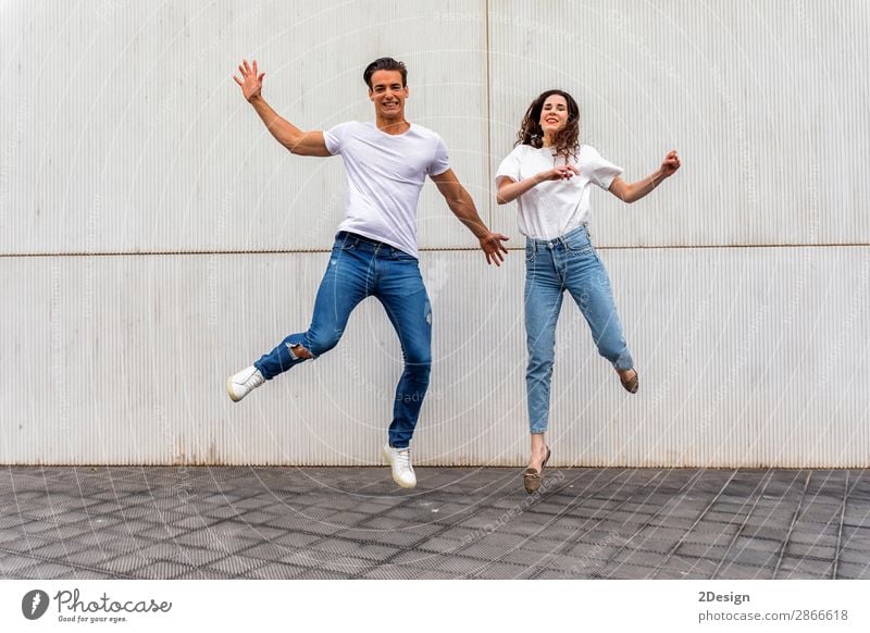 Happy couple in love jumping against grey wall. Lifestyle Joy Leisure and hobbies House (Residential Structure) Human being Masculine Feminine Young woman