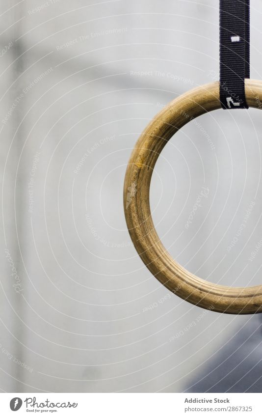 Detail of a set of black gymnastic rings or steady rings hanging in home gym  over a white wall on the right side of frame. Empty space for text. Fitness  or healthy