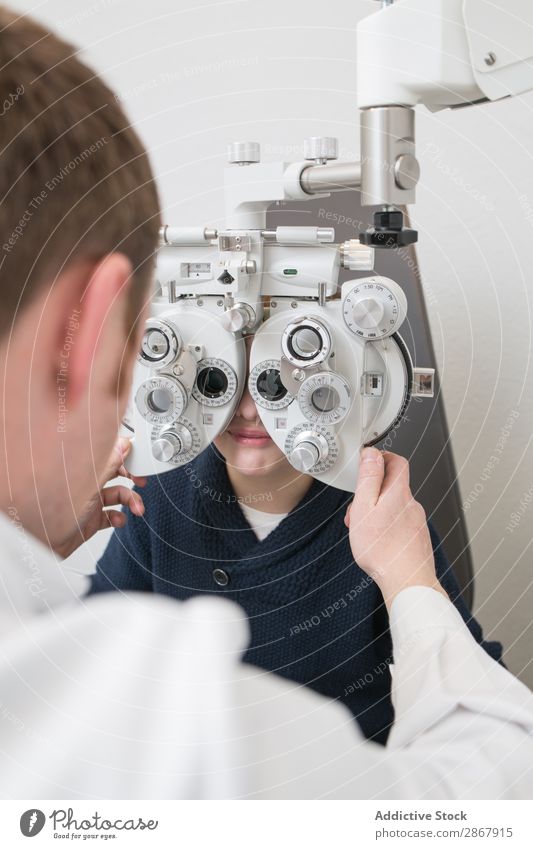 Optician testing a boy's eyes Boy (child) Child clinic device diagnose Display Doctor Examinations and Tests Eyes Person wearing glasses Healthy Hospital