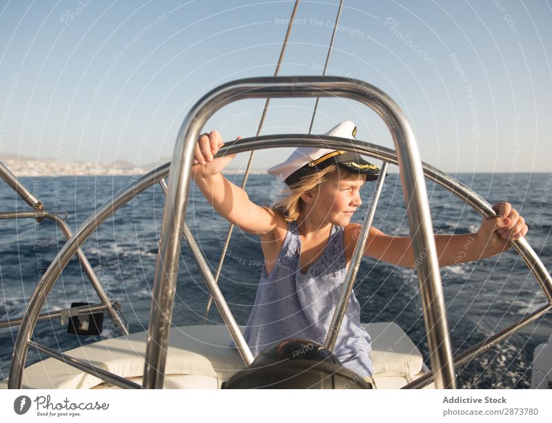 Smiling girl holding steering wheel on yacht on water Girl Yacht Water Steering wheel Captain Hat Ocean Child Floating Beautiful weather Watercraft Expensive