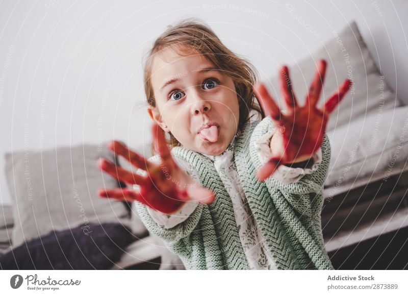 Girl with dirty hands showing tongue in room Hand Dirty Colour making face Tongue Room Sofa Indicate Painting (action, artwork) Funny Child Decoration