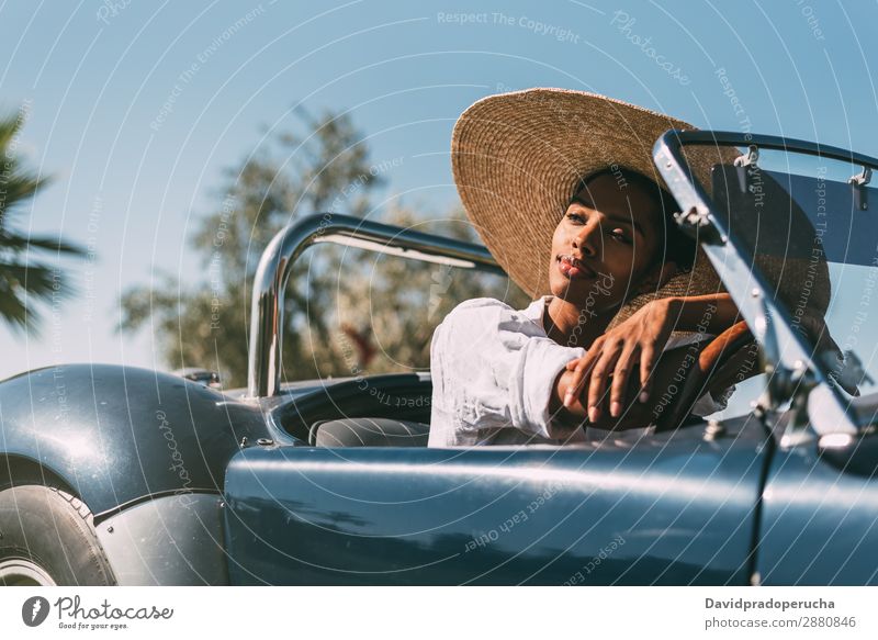 Black woman driving a vintage convertible car Woman Car Driving right steering wheel Ethnic Happy Convertible Street united kingdom Luxury Looking away