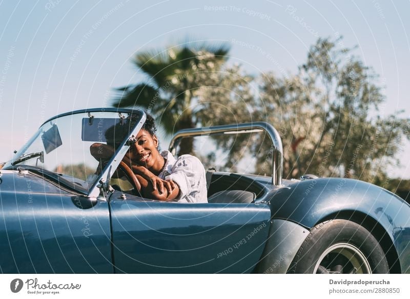 Black woman driving a vintage convertible car Woman Car Driving Happy Ethnic Convertible Street Luxury Looking into the camera Profile Cheerful Smiling Classic