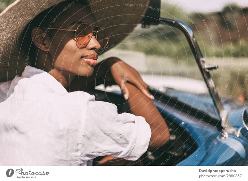 Black woman driving a vintage convertible car Woman Car Driving right steering wheel Ethnic Happy Convertible Street united kingdom Luxury Looking away