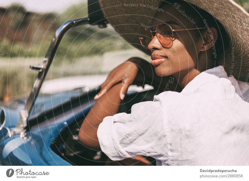 Black woman driving a vintage convertible car Woman Car Driving Ethnic Happy Convertible Street Luxury Looking away Smiling Classic 60's Beautiful Straw hat