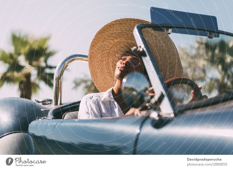 Black woman driving a vintage convertible car Woman Car Happy Driving right steering wheel Ethnic Convertible Street united kingdom Luxury Straw hat Sunglasses