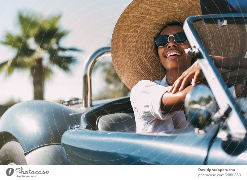 Black woman driving a vintage convertible car Woman Car Driving right steering wheel Ethnic Convertible Street united kingdom Vintage Front view Luxury