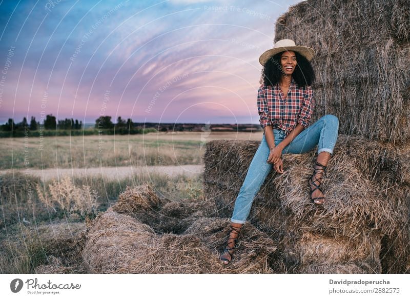 Happy black young woman sitting on a pile of hay Woman Farmer Hay Summer Ethnic Black African Landscape Nature Countries Sky Relaxation Lifestyle