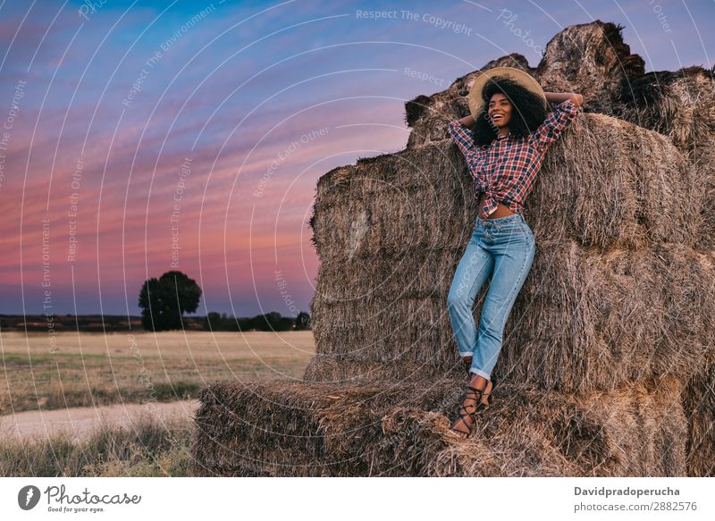 Happy black young woman standing on a pile of hay Woman Farmer Hay Summer Ethnic Black African Landscape Nature Countries Sky Relaxation Lifestyle