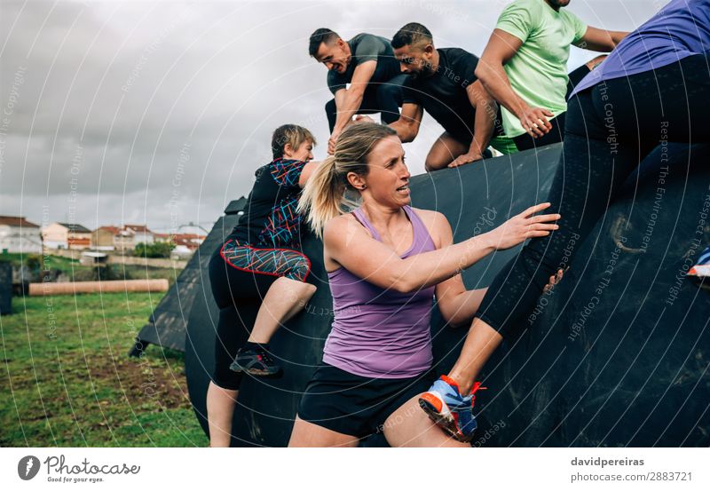 Group of participants in an obstacle course climbing a drum Lifestyle Sports Climbing Mountaineering Human being Woman Adults Man Authentic Strong Black Effort