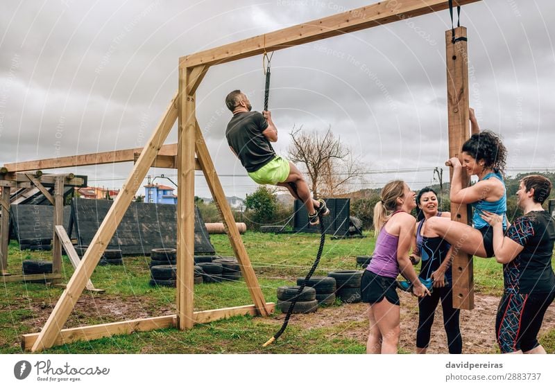 Participants in obstacle course doing pegboard and climbing rope Lifestyle Joy Sports Human being Woman Adults Man Group Wood Laughter Authentic Strong Black