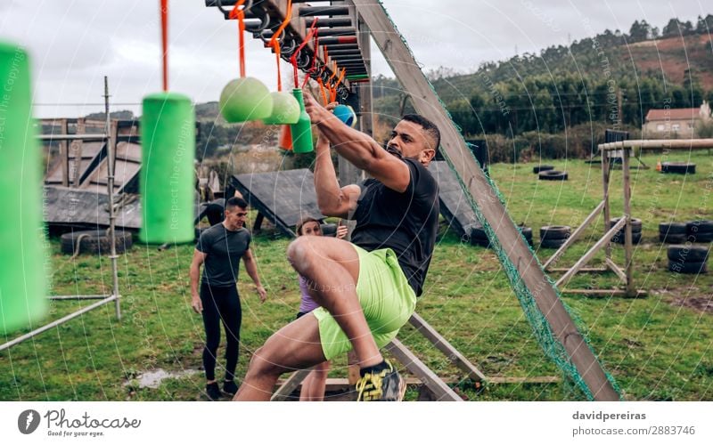 Man in obstacle course doing suspension exercises Sports Human being Woman Adults Arm Group Fitness Hang Authentic Strong Black Power Effort Competition