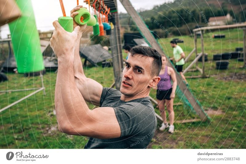 Man in obstacle course doing suspension exercises Sports Human being Woman Adults Arm Group Observe Fitness Hang Authentic Strong Power Effort Competition
