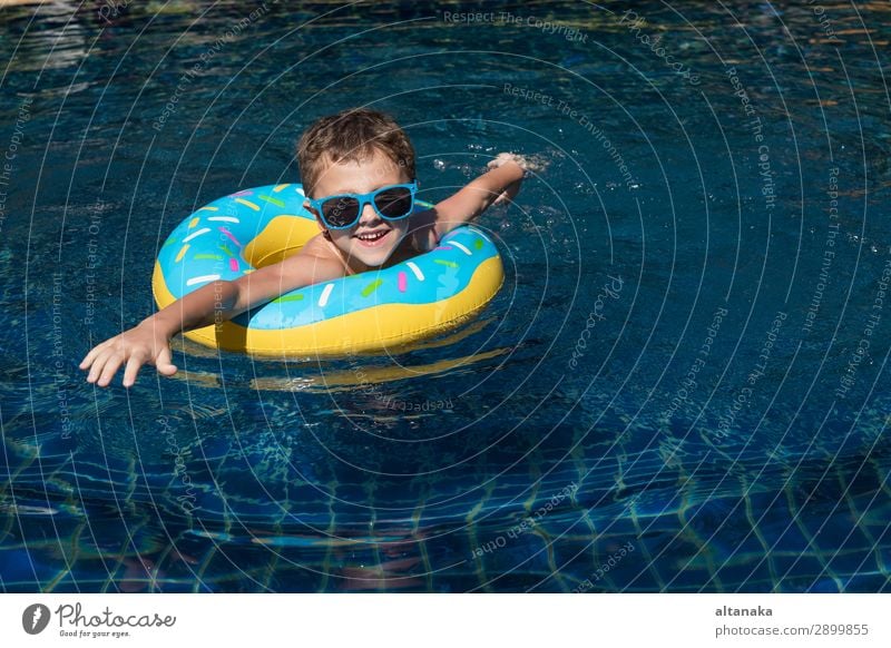 One little happy boy playing on the inflatable circle in swimming pool at the day time. Concept of friendly family. Lifestyle Joy Happy Face Relaxation