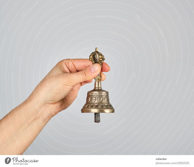 female hand holding a bronze bell for alternative medicine Lifestyle Alternative medicine Harmonious Relaxation Meditation Yoga Metal Old Brown Gray Health care