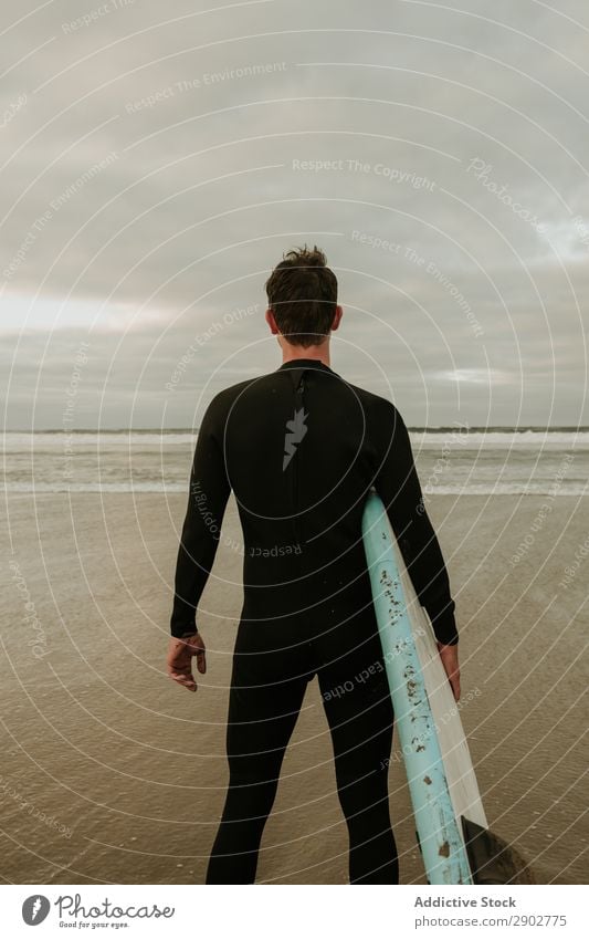 Person with surfboard standing near sea Human being Stand Surfboard Ocean Sand Wet Clouds Sky Lanzarote Spain Vacation & Travel Trip Leisure and hobbies