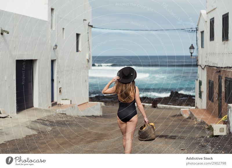 Anonymous female on small street of coastal town Woman Town Ocean Shabby Street Lanzarote Spain Vacation & Travel Hat Touch admiring Rest Relaxation