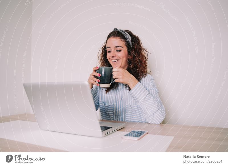 brunette woman is using her computer while having a coffee Coffee Lifestyle Happy Desk Table Work and employment Office Business Telephone Computer Notebook