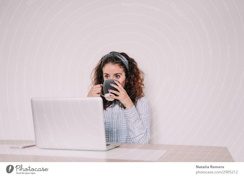 brunette woman is using her computer while having a coffee Coffee Lifestyle Happy Desk Table Work and employment Office Business Telephone Computer Notebook