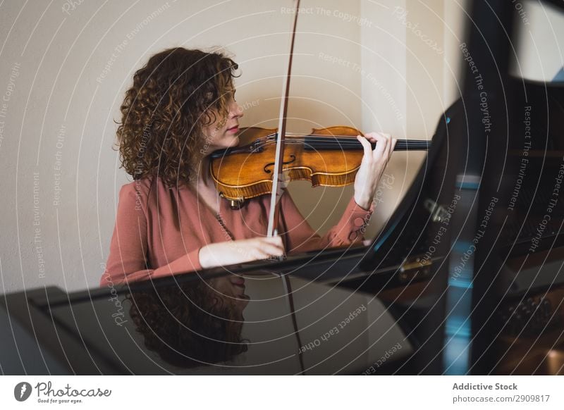 Woman sitting next to a piano playing a violin Fiddle Playing Music Violinist Orchestra instrument Classical Musician Hand Musical Human being String