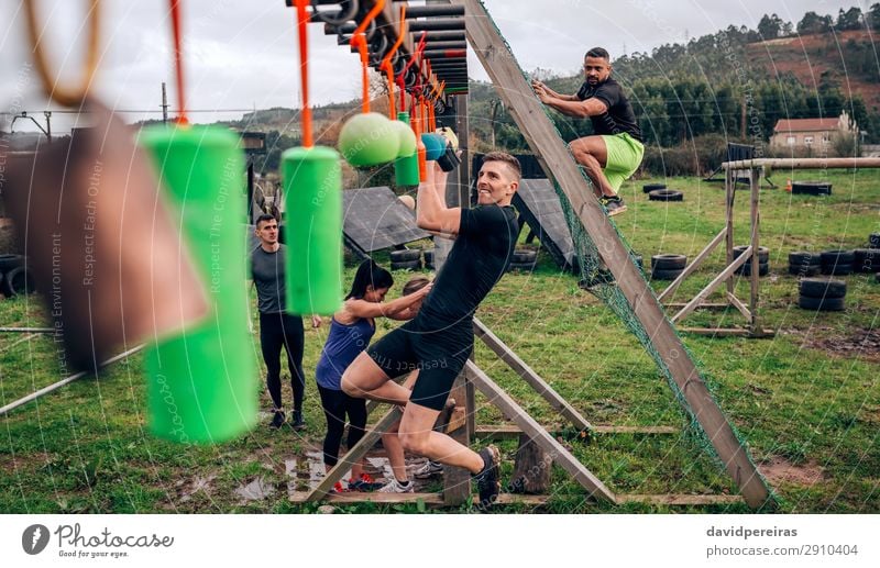 Man in obstacle course doing suspension exercises Sports Human being Woman Adults Arm Group Observe Fitness Hang Authentic Strong Black Power Effort Competition