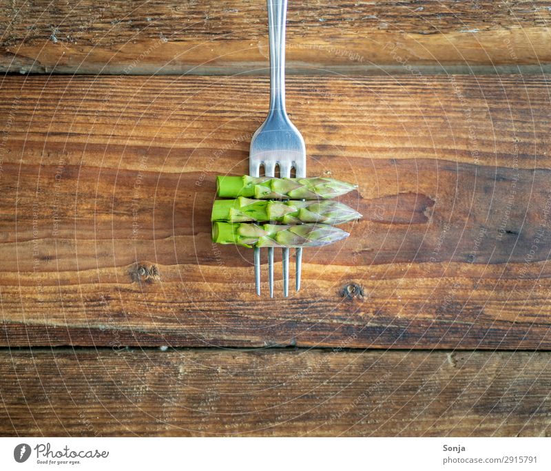 Green asparagus on a fork Food Vegetable Nutrition Vegetarian diet Diet Fasting Fork Healthy Eating Wooden table Spring fever To enjoy Asparagus Rustic style