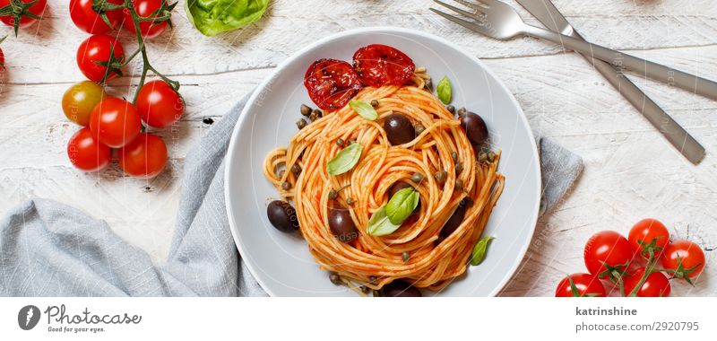 Spaghetti with tomato sauce olives and capers Vegetable Lunch Dinner Vegetarian diet Plate Fork Spoon Wood Above Green Red Tradition pasta puttanesca Olive
