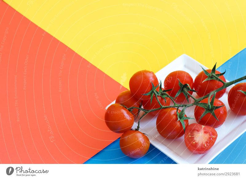 Cherry tomatoes on a blue, yellow and coral red background Vegetable Vegetarian diet Diet Fresh Bright Above Blue Yellow Red cherry tomatoes Ingredients Raw