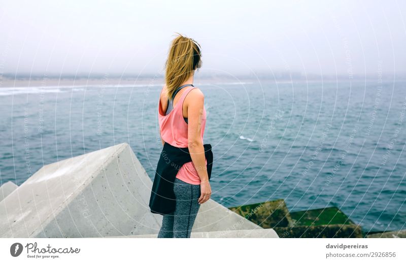 Unrecognizable young woman watching the sea Lifestyle Wellness Relaxation Calm Ocean Sports Human being Woman Adults Fog Concrete Observe Fitness Athletic