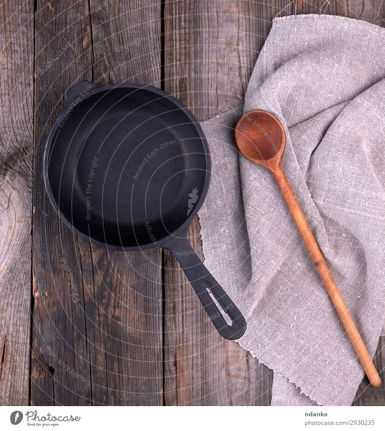 empty black round frying pan with handle Pan Spoon Table Kitchen Wood Metal Old Above Clean Brown Gray Black background board Cast cooking cookware Culinary