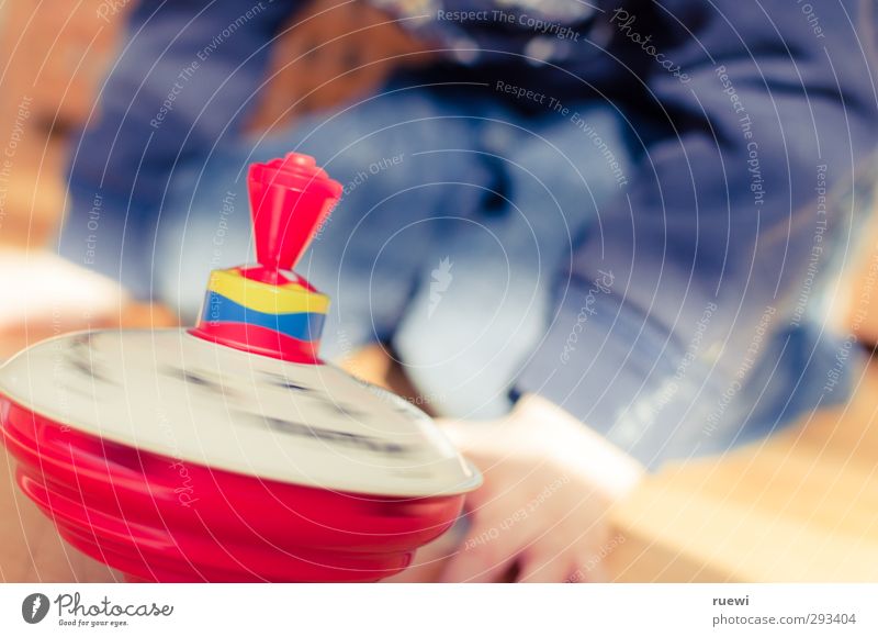 Humming top in motion with child in background Leisure and hobbies Playing Children's game Tin toy Gyroscope Human being Masculine Boy (child) Infancy Life 1