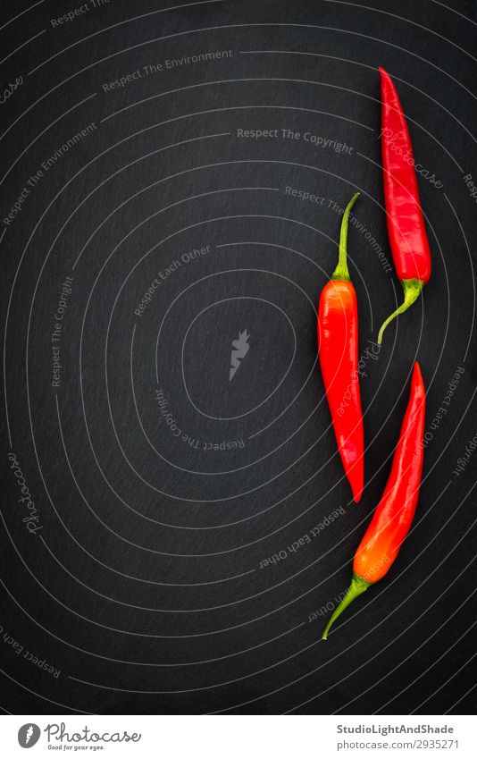 Three red chili peppers on dark background Vegetable Herbs and spices Eating Vegetarian diet Healthy Eating Dark Simple Fresh Hot Cold Natural Green Red Black