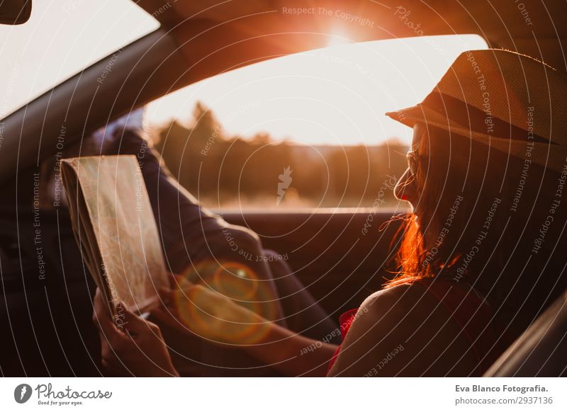 Modern girl resting in a car reading a map at sunset Lifestyle Joy Relaxation Leisure and hobbies Reading Vacation & Travel Trip Adventure Summer Sun