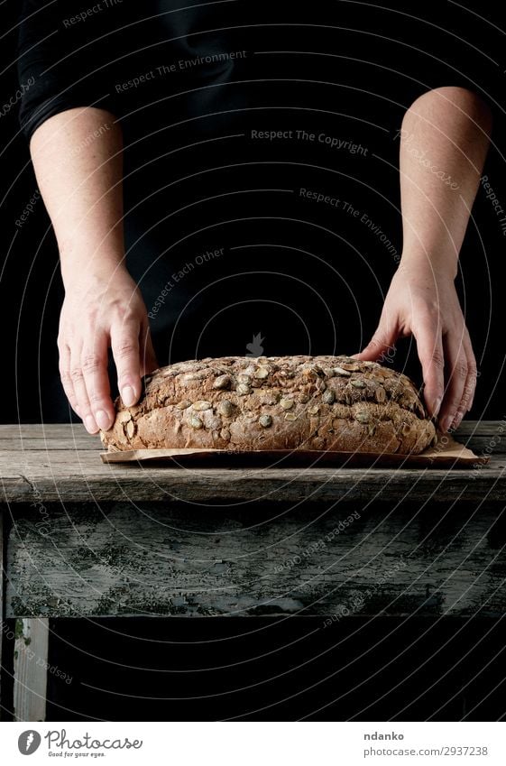 female hands hold oval baked rye bread Dough Baked goods Bread Roll Nutrition Eating Breakfast Table Kitchen Woman Adults Hand Warmth Wood Make Dark Fresh