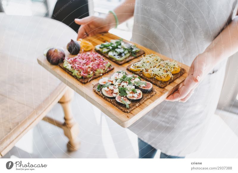 Woman carying wooden board with healthy sandwiches Cheese Fruit Bread Breakfast Lunch Hand Joy toast Sandwich herbs Fig food Apron cooking chef Snack Dish feta