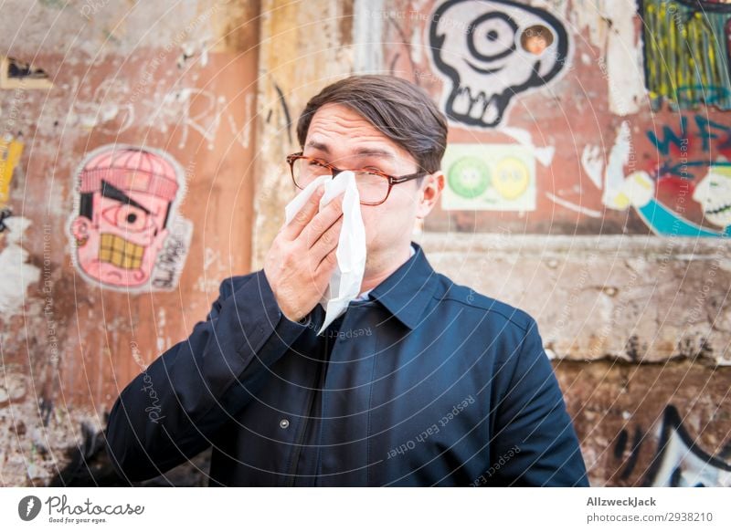 young man is ill and wipes his nose Wall (building) Portrait photograph Young man Close-up Face Common cold Illness Blow one's nose Handkerchief Breathe Coat