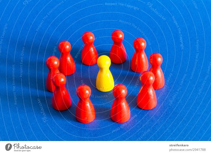 A single yellow playing piece stands in a circle of red playing pieces on a blue background Playing Group Toys Wood Select Observe Advice To talk Threat