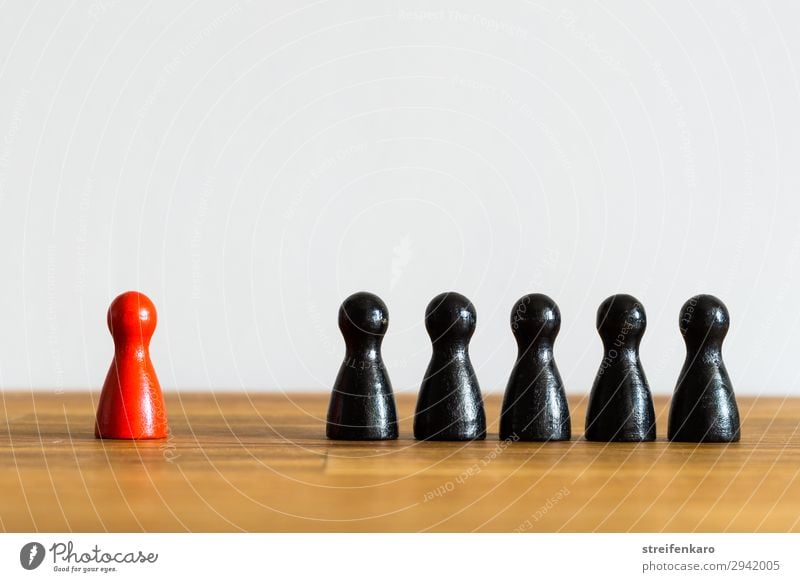 A single red figure stands apart from a row of black figures on a wooden background Playing Board game Group Toys Wood Red Black Together Help Curiosity