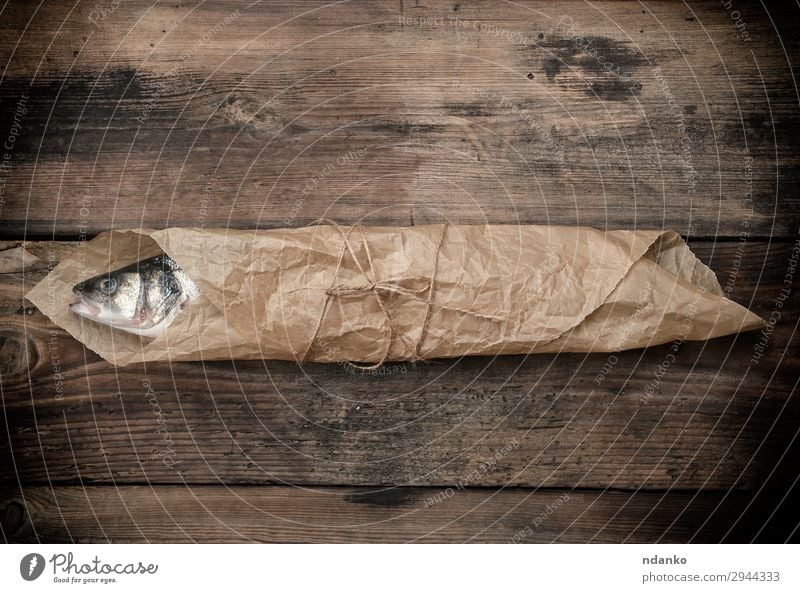 sea bass fish wrapped in a brown paper Seafood Nutrition Ocean Table Kitchen Rope Animal Paper Wood Eating Fresh Above Brown Gray bag board cooking labrax one