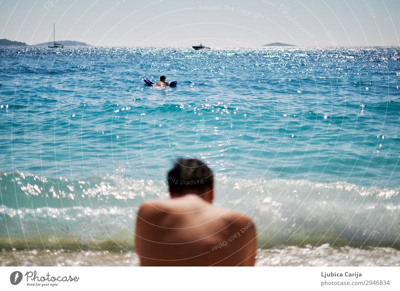 Young man sitting on a beach and looking at the waves Relaxation Summer Swimming & Bathing Sailing Human being Masculine Youth (Young adults) Back 2 Water Sky