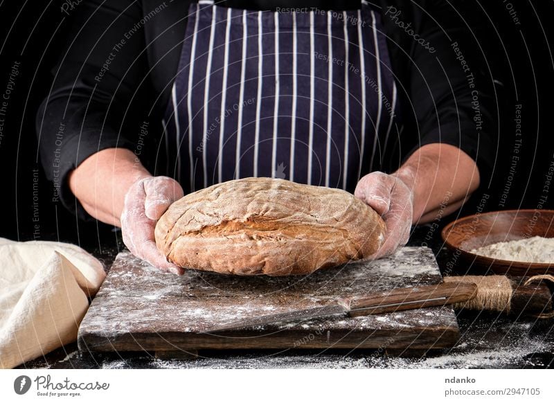 male hands are holding brown rye bread Dough Baked goods Bread Nutrition Eating Lunch Dinner Knives Table Kitchen Cook Man Adults Hand Wood Make Dark Fresh