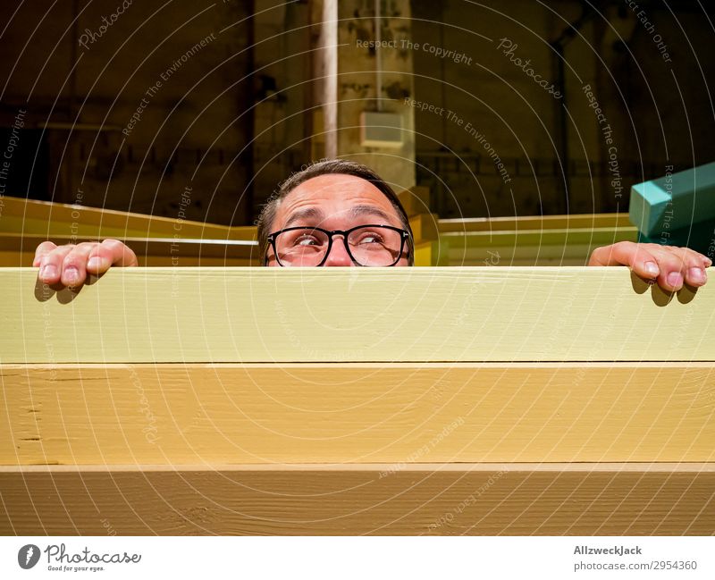 Young man looks curiously over a barrier Interior shot 1 Person Artificial light Portrait photograph Forward Looking into the camera Eyeglasses Fence Barrier