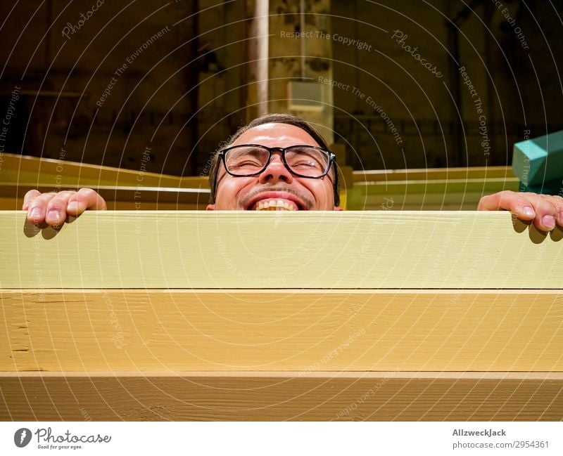 Young man looking over a barrier Interior shot 1 Person Artificial light Portrait photograph Forward Looking into the camera Eyeglasses Fence Barrier