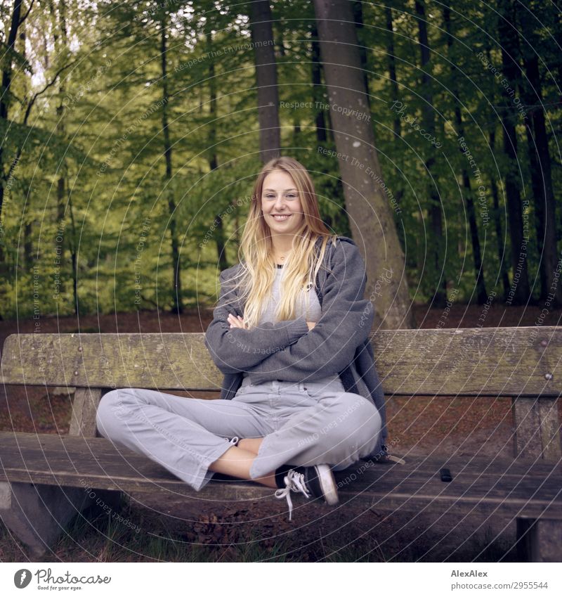 Young woman sitting cross-legged on a bench in a forest and smiling into the camera Joy pretty Wellness Life Trip Youth (Young adults) 18 - 30 years Adults