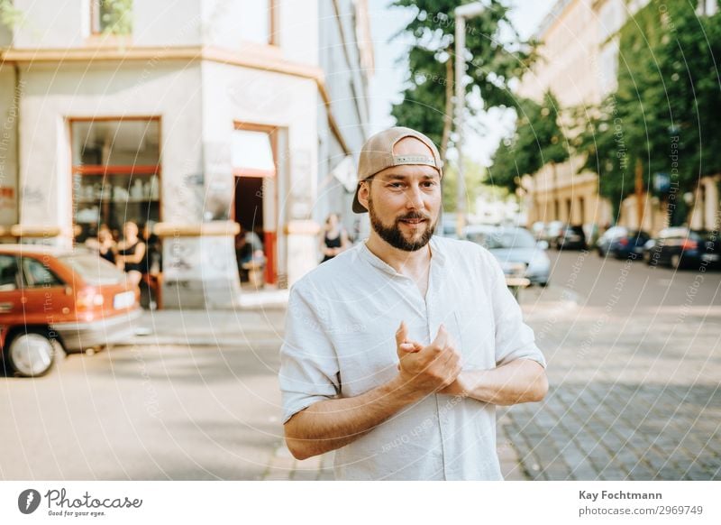 man wearing basecap standing on the street attractive baseball beard bearded casual caucasian cheerful citylife confident cool emotion expression face fashion