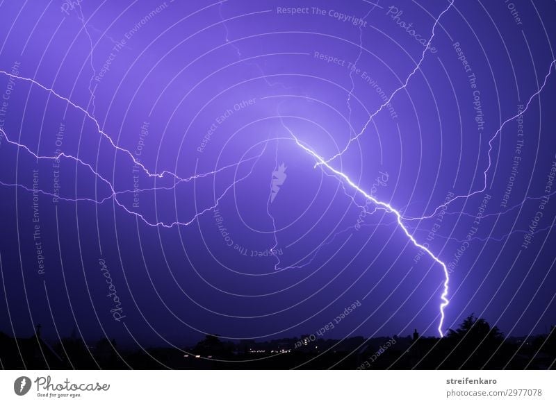Bright flash of lightning in a blue night sky over the city silhouette Environment Nature Elements Air Sky Night sky Weather Bad weather Storm