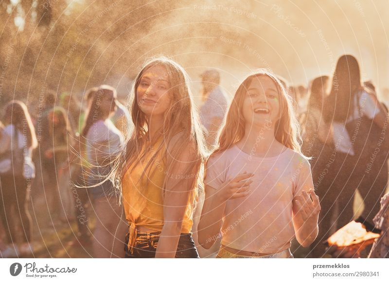 Portrait of happy smiling young girls with colorful paints on faces and clothes. Two friends spending time on holi color festival Lifestyle Style Joy Happy