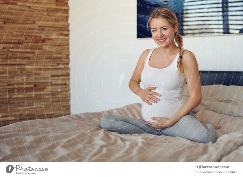 Happy pregnant woman sitting on a bed Child Feminine Baby Woman Adults Mother Family & Relations 1 Human being 18 - 30 years Youth (Young adults) Blonde Smiling